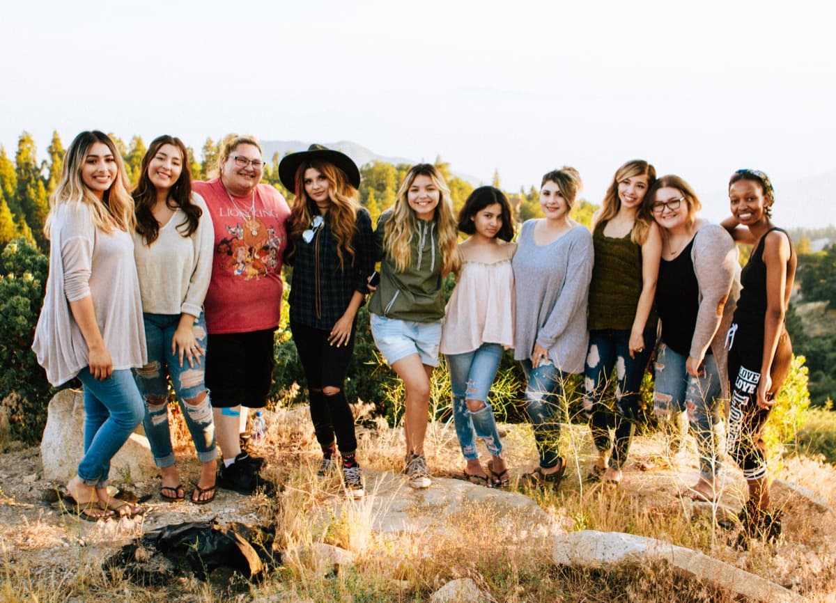 A group of women smiling together outdoors in golden-hour light