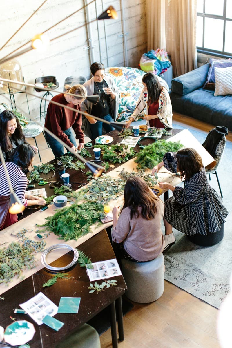 A small group of women gathered around a table, working on a shared hands-on project together