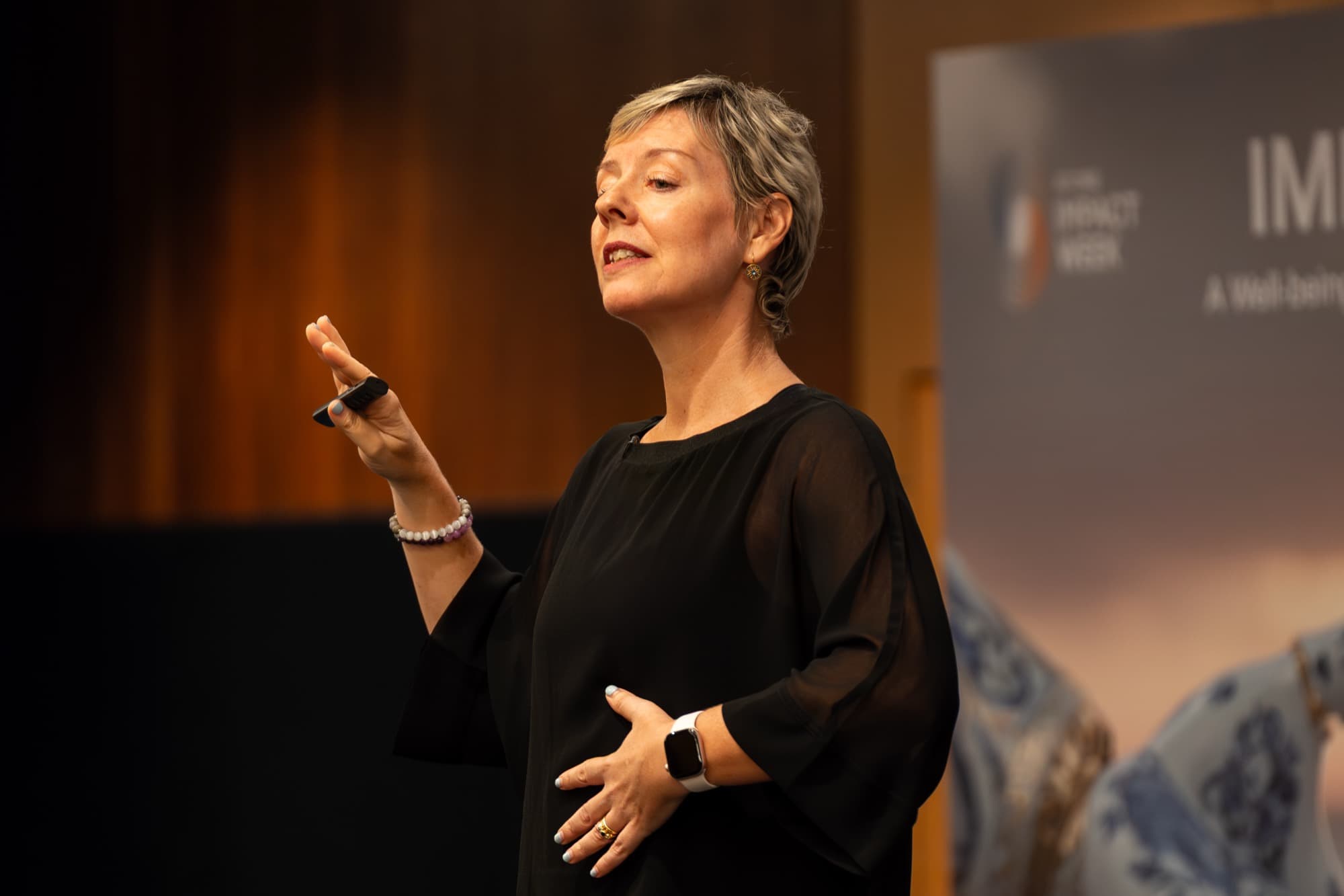 Nicole Glisson mid-gesture, speaking at a wellbeing conference